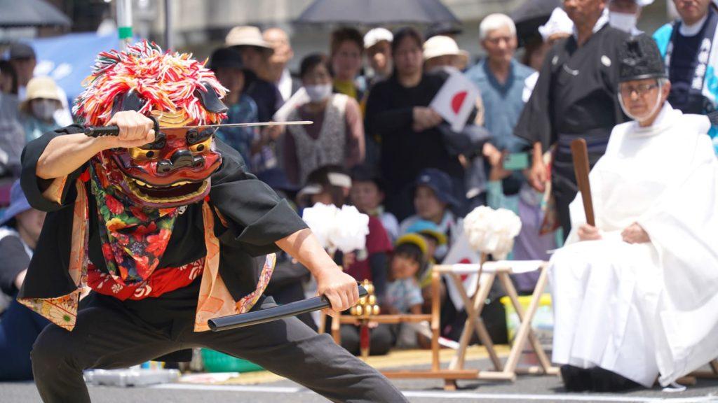 獅子舞踊りをする人と、それを眺める人々